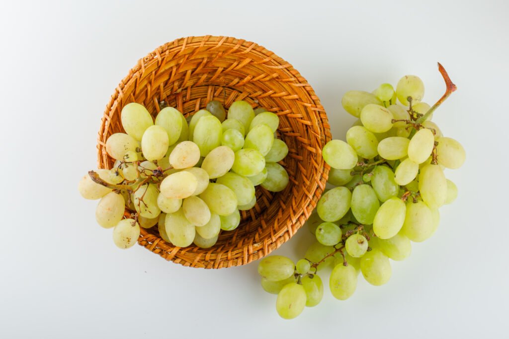 green grapes in a wicker basket on a white background. flat lay.